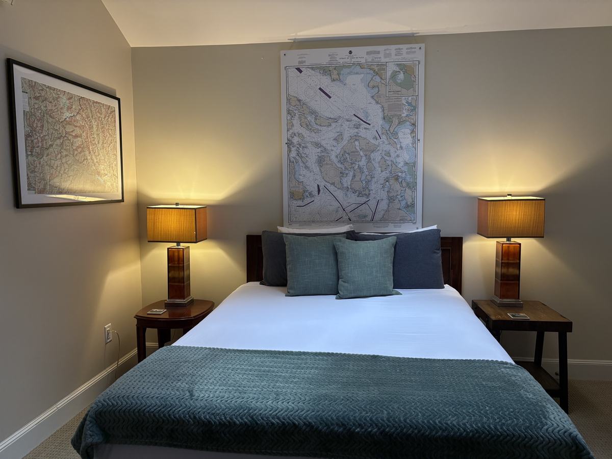 The queen bed seen head-on, centered under the nautical chart between two glowing amber lamps